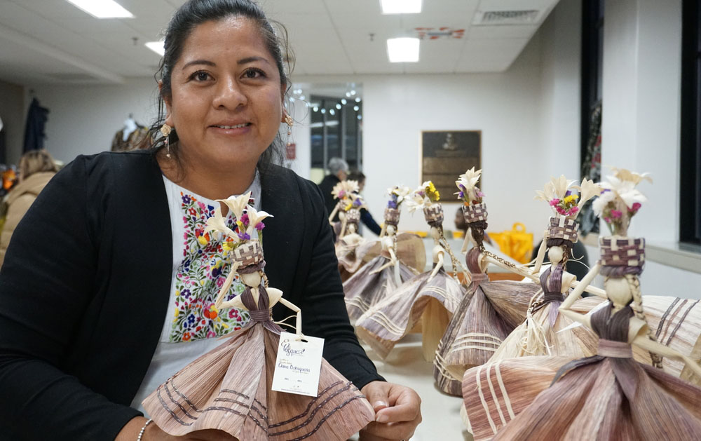 A woman showing off her handmade corn husk dolls.