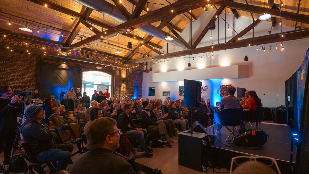  An attentive crowd listens to a discussion between musicians during a community festival.