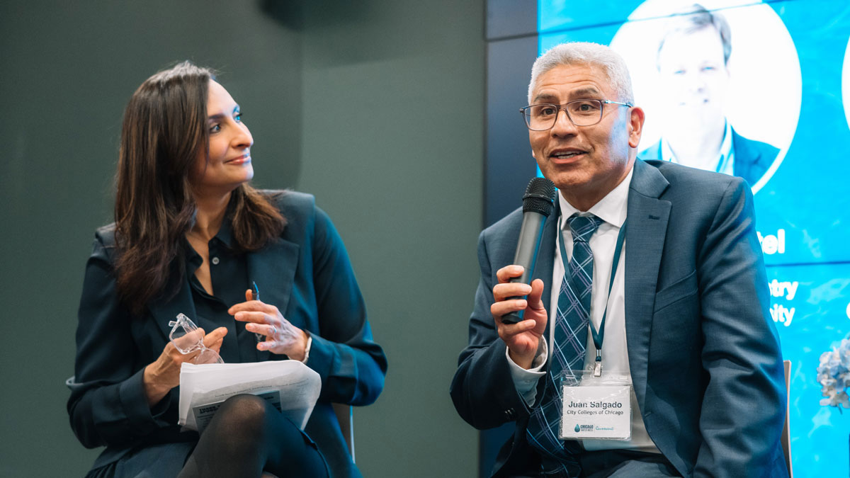 A close image of a woman and man at a public speaking event. Both are seated side-by-side and the man holds a microphone.  