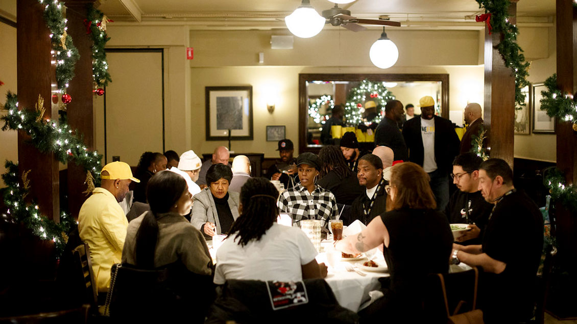 Group of people sitting around a dining table in a holiday-decorated restaurant.