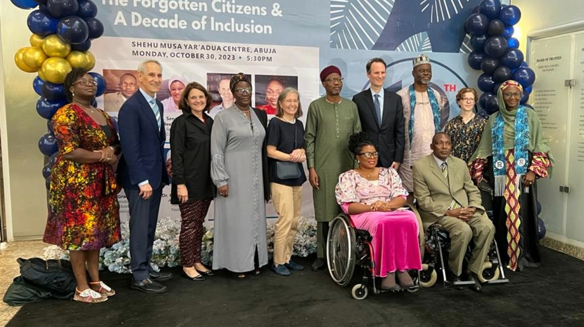 MacArthur Foundation and Inclusive Friends Association's staff members in front of event banner.