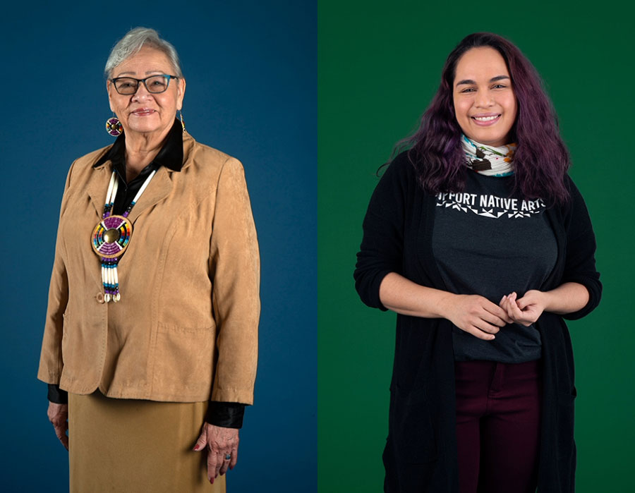 Two women standing; the woman on the left is wearing a tan suit and beaded necklace, the woman on the right has a black cardigan.