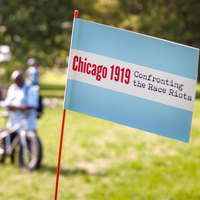 Chicago_1919_Confronting_the_Race_Riots_Flag_In_Foreground_With_Blurry_Cyclists_And_Green_Landscape_In_Background